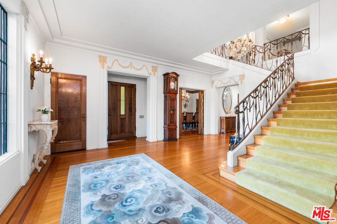 The grand foyer with green-runner staircase, wrought-iron Art Deco railings and crystal chandelier.