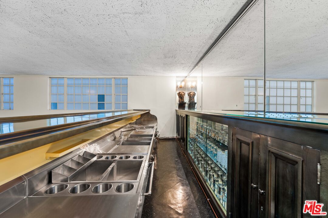 The seventeen-foot stainless steel entertainment bar with mirrored back wall and glass-block sconces.