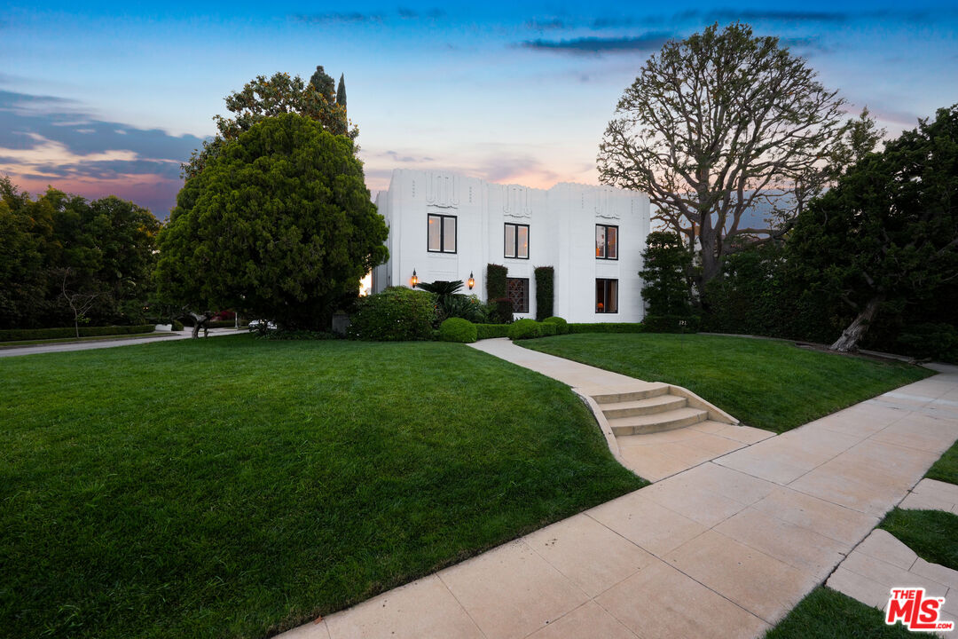 The Smith House at dusk, viewed across the manicured front lawn with mature pines silhouetted against a violet sky.